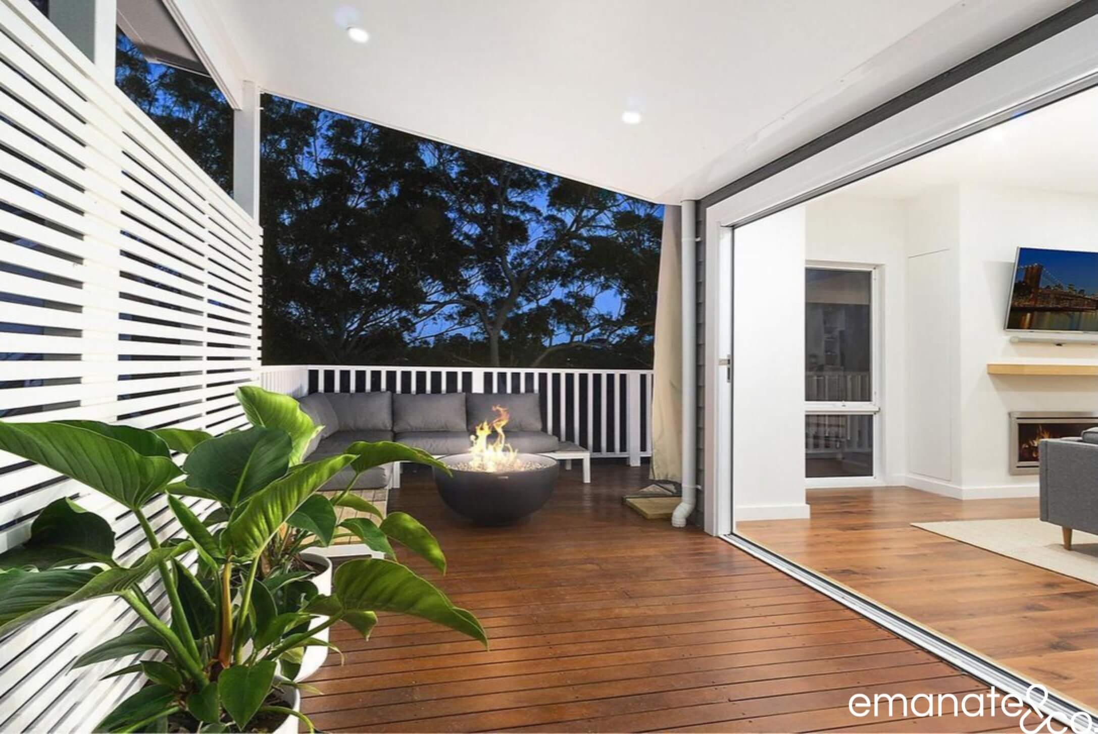 Small cosy alfresco living space with bi-fold doors leading out to a timber deck & patio cover in Hornsby, Sydney