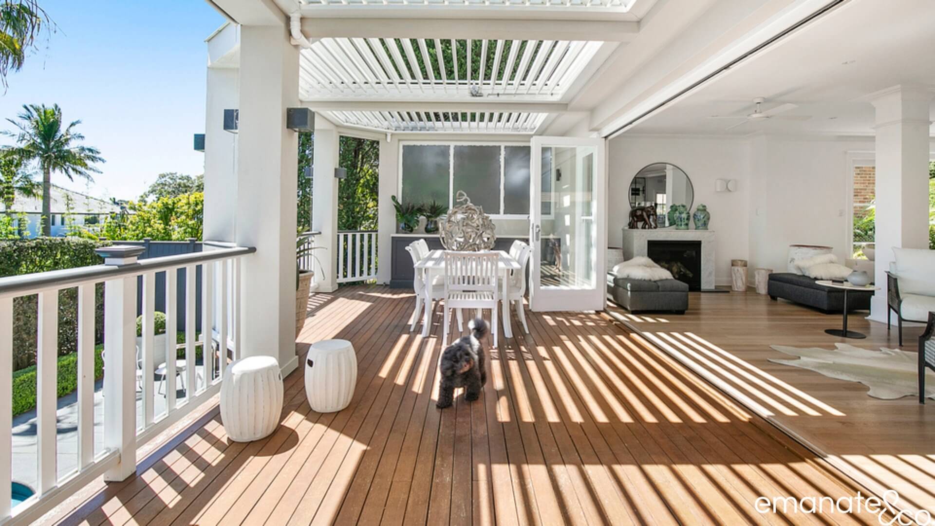 Wide timber bi-fold doors leading out to a timber deck covered with a louvered patio, Sydney