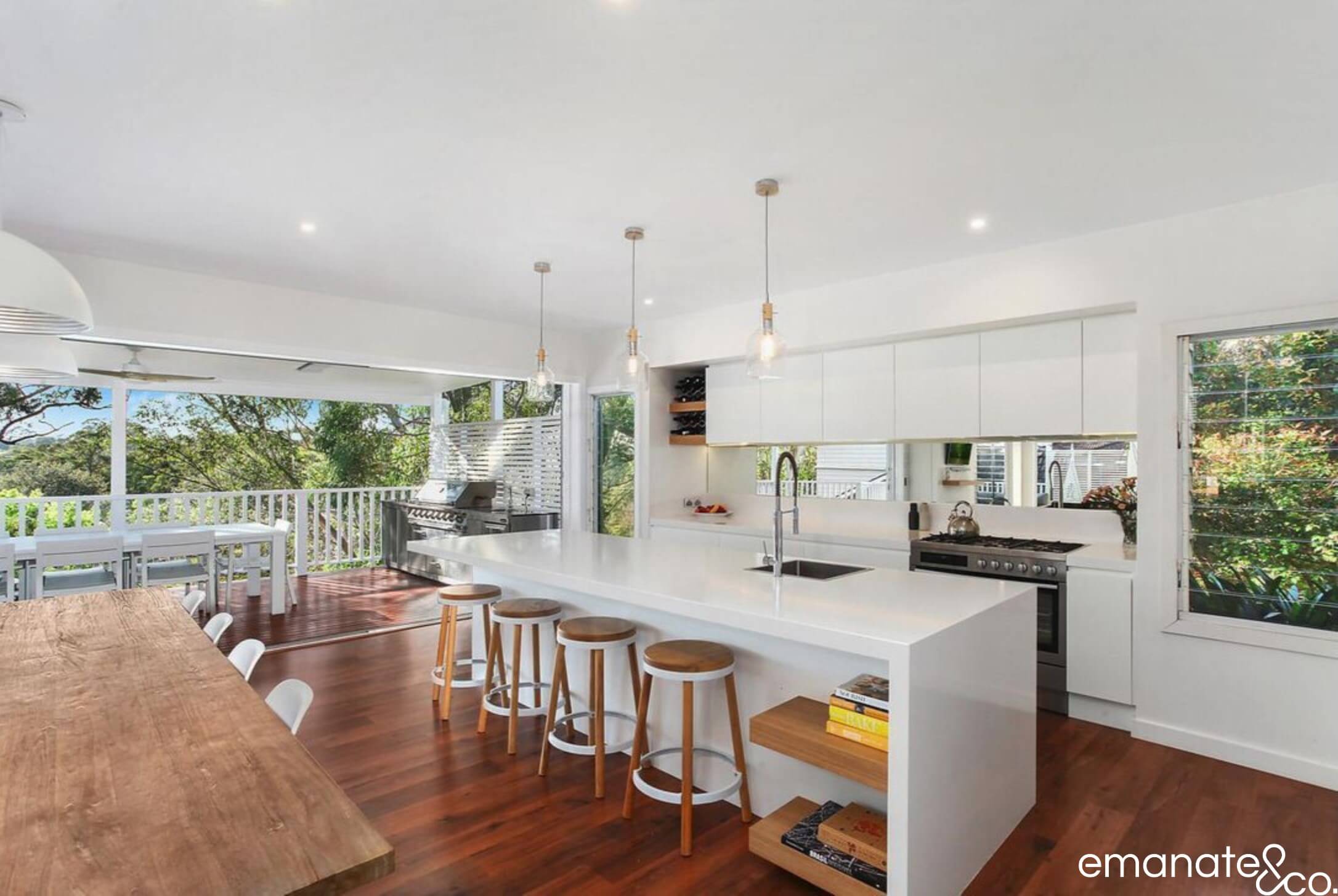 Elegant outdoor kitchen and dining area with a built-in barbecue, glass balustrades, and modern seating, designed for stylish outdoor entertaining.